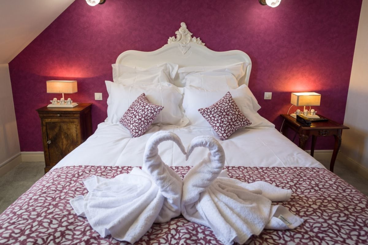 A hotel room with a bed, two bedside tables, and a decorative towel arrangement.