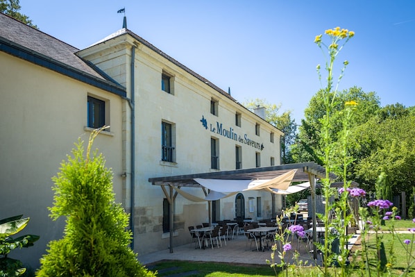 Un edificio con terraza al aire libre y un letrero que dice "Le Moulin des Saveurs".