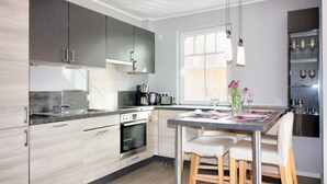 A modern kitchen with a central island, stainless steel appliances, and a window providing natural light. - Carolin Dangast (Varel)
