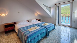 Une chambre avec deux lits, un balcon et une vue sur l’extérieur.