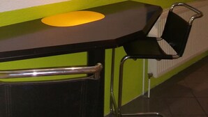 Een eethoek met een tafel, stoelen, een schilderij van citrusvruchten en een radiator.
