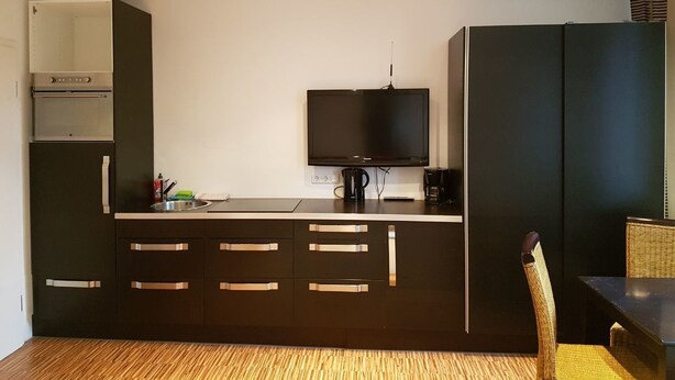 Een moderne keuken met een inbouwoven, magnetron en een flatscreen televisie.
