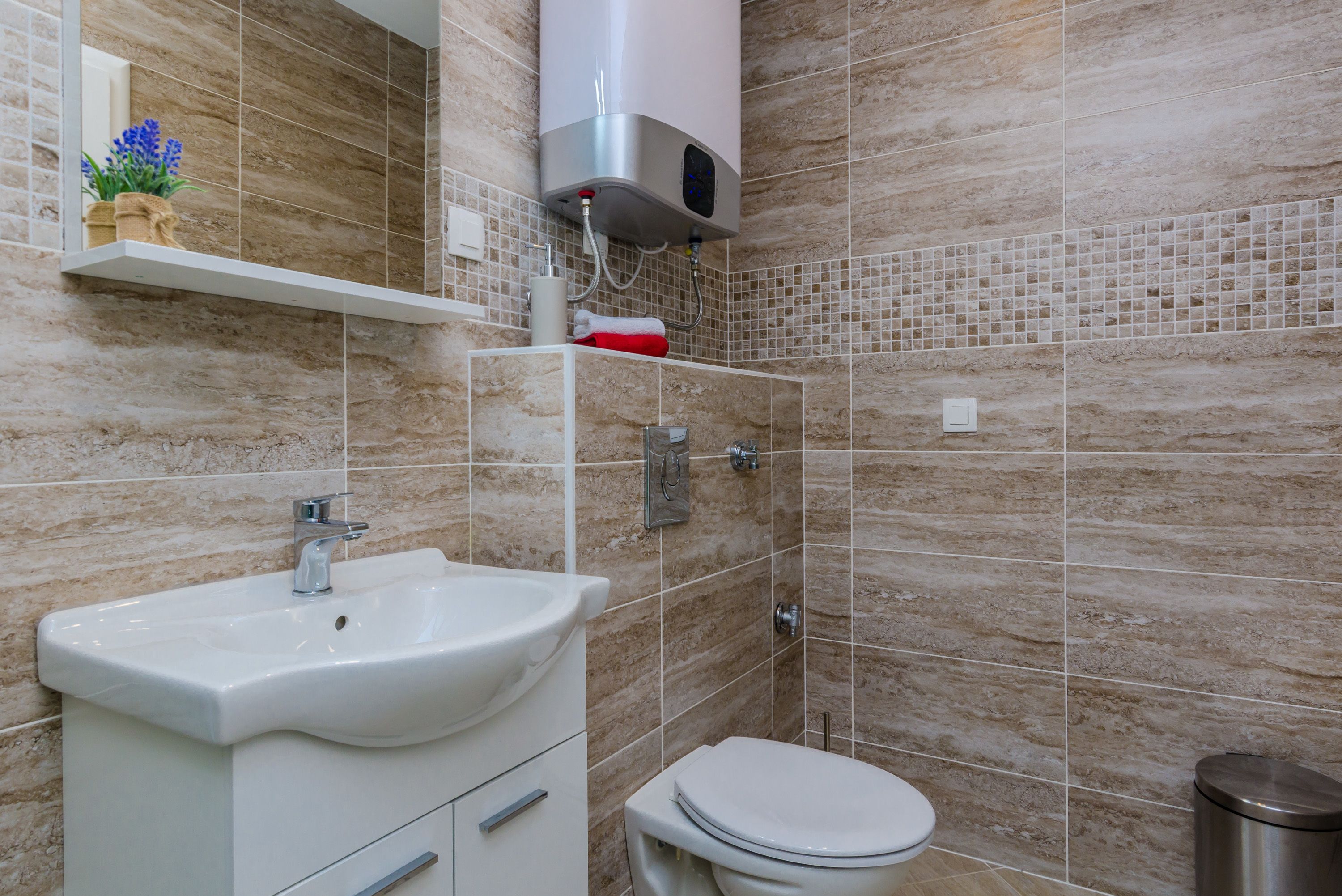 Et moderne badeværelse med en hvid vask, toilet og bruseområde.