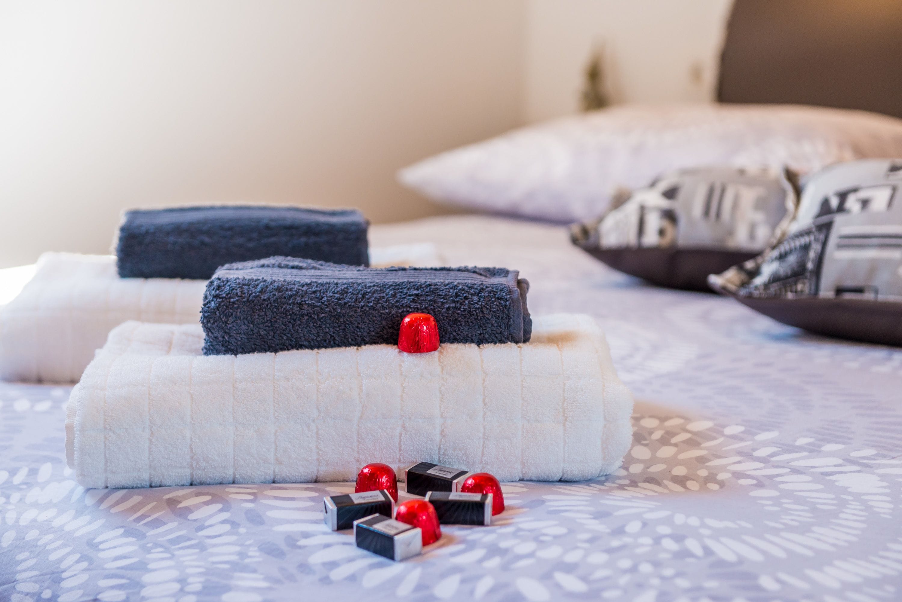 A neatly arranged bed with folded towels and decorative items on a patterned bedspread.