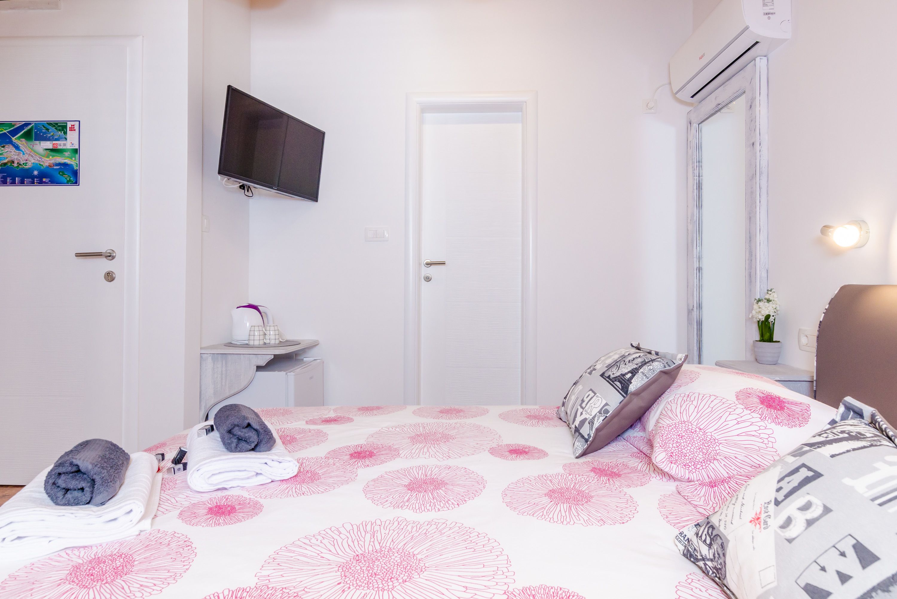 Camera d'albergo con un letto, una televisione a muro, una porta e un condizionatore d'aria.