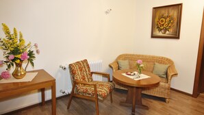 A room with a wooden table, a wicker sofa, a chair, and a radiator. - Gasthaus Metzgerei Zur Linde (Kenzingen)