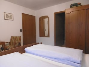 A bedroom with a bed, a chair, a wooden wardrobe, and a mirror on the wall. - Gasthaus Metzgerei Zur Linde (Kenzingen)