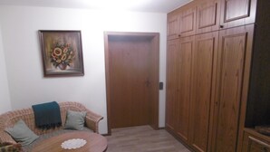 A living room with a sofa, a round wooden table, a door, and wooden cabinets. - Gasthaus Metzgerei Zur Linde (Kenzingen)