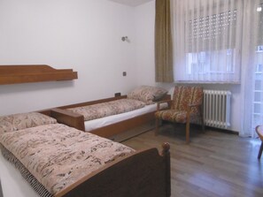 A small, simple room with a wooden bed, a chair, and a radiator. - Gasthaus Metzgerei Zur Linde (Kenzingen)