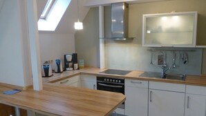 A modern kitchen with a wooden countertop, stainless steel appliances, and a skylight. - Antonia Rerik (Rerik)
