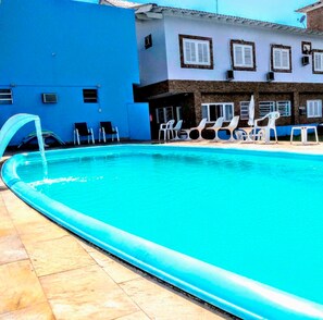 Una piscina al aire libre, sombrillas, sillones reclinables de piscina