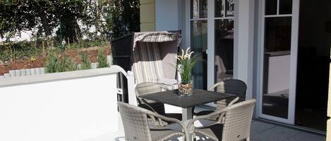 An outdoor patio with wicker furniture, a table, and a covered seating area.
