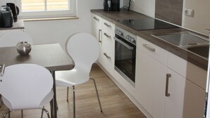 Une cuisine moderne avec des armoires blanches, un four encastré et une fenêtre donnant sur l’extérieur.
