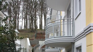 Un bâtiment moderne doté d’un balcon incurvé, d’un escalier menant à l’étage supérieur et d’une allée pavée.