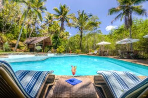 A pool area with lounge chairs and umbrellas, surrounded by palm trees. - Itacaré Eco Resort (Itacaré)