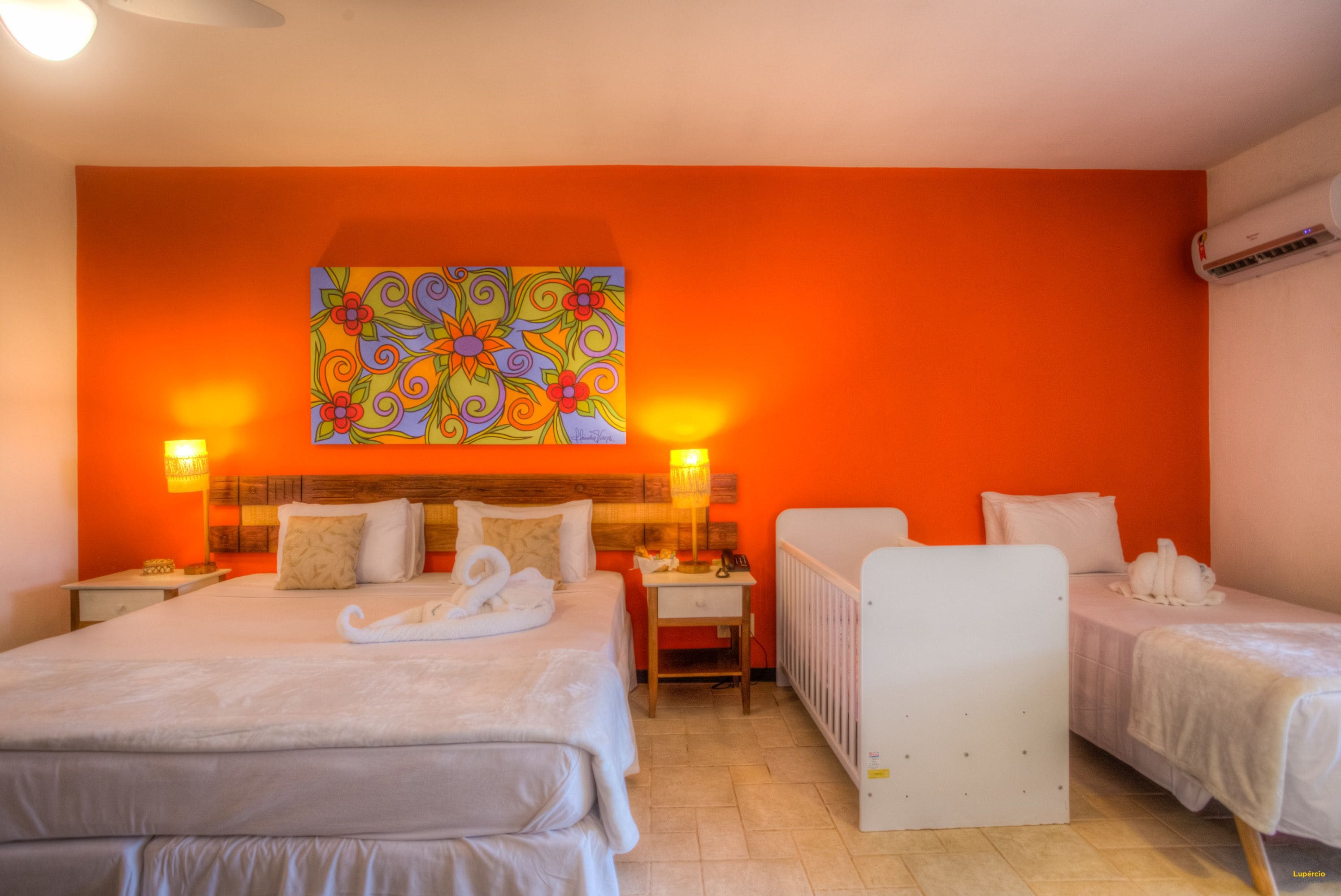 Una habitación de hotel con una cama grande, dos mesitas de noche, un escritorio y un radiador.