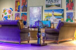 Una habitación con mobiliario de mimbre, una mesa con un objeto decorativo y obras de arte en las paredes.