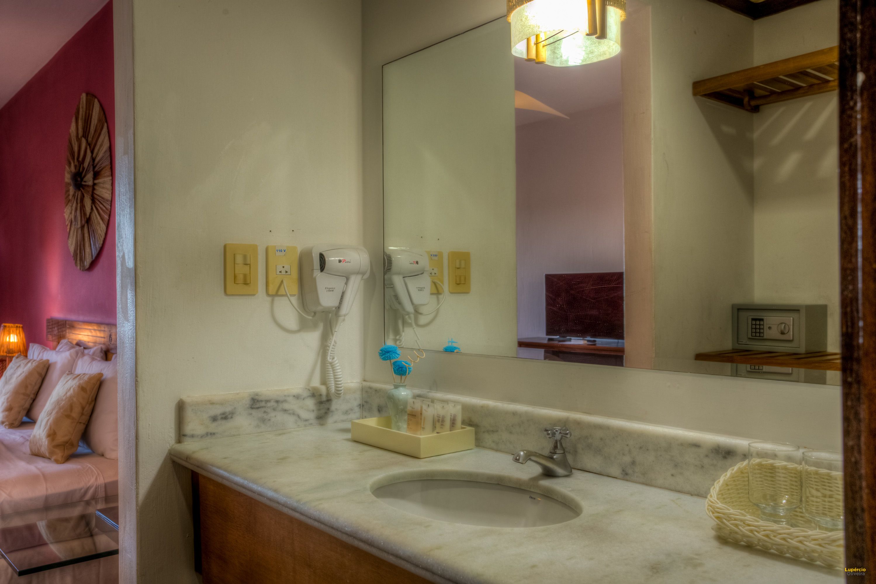 A bathroom with a marble sink, a mirror, a hairdryer, and a towel rack.