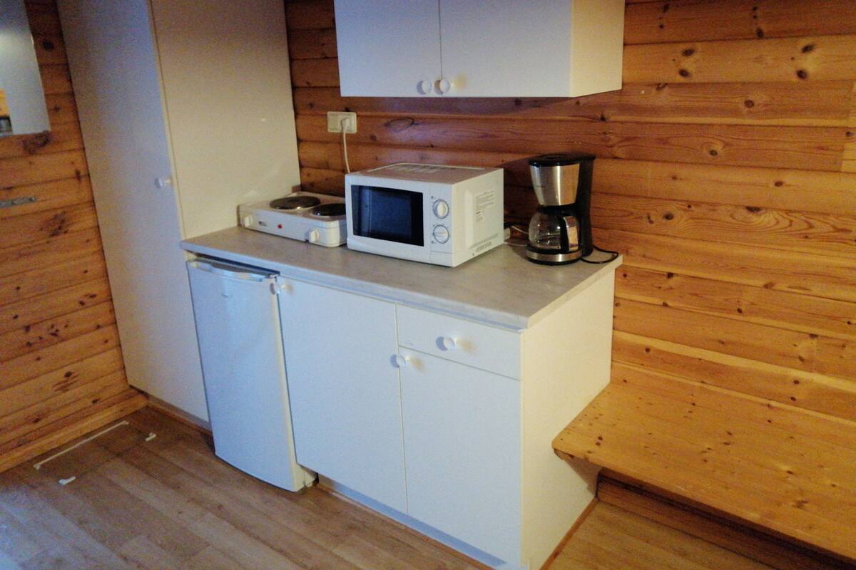 Una kitchenette compacta equipada con microondas, cafetera y refrigerador pequeño.