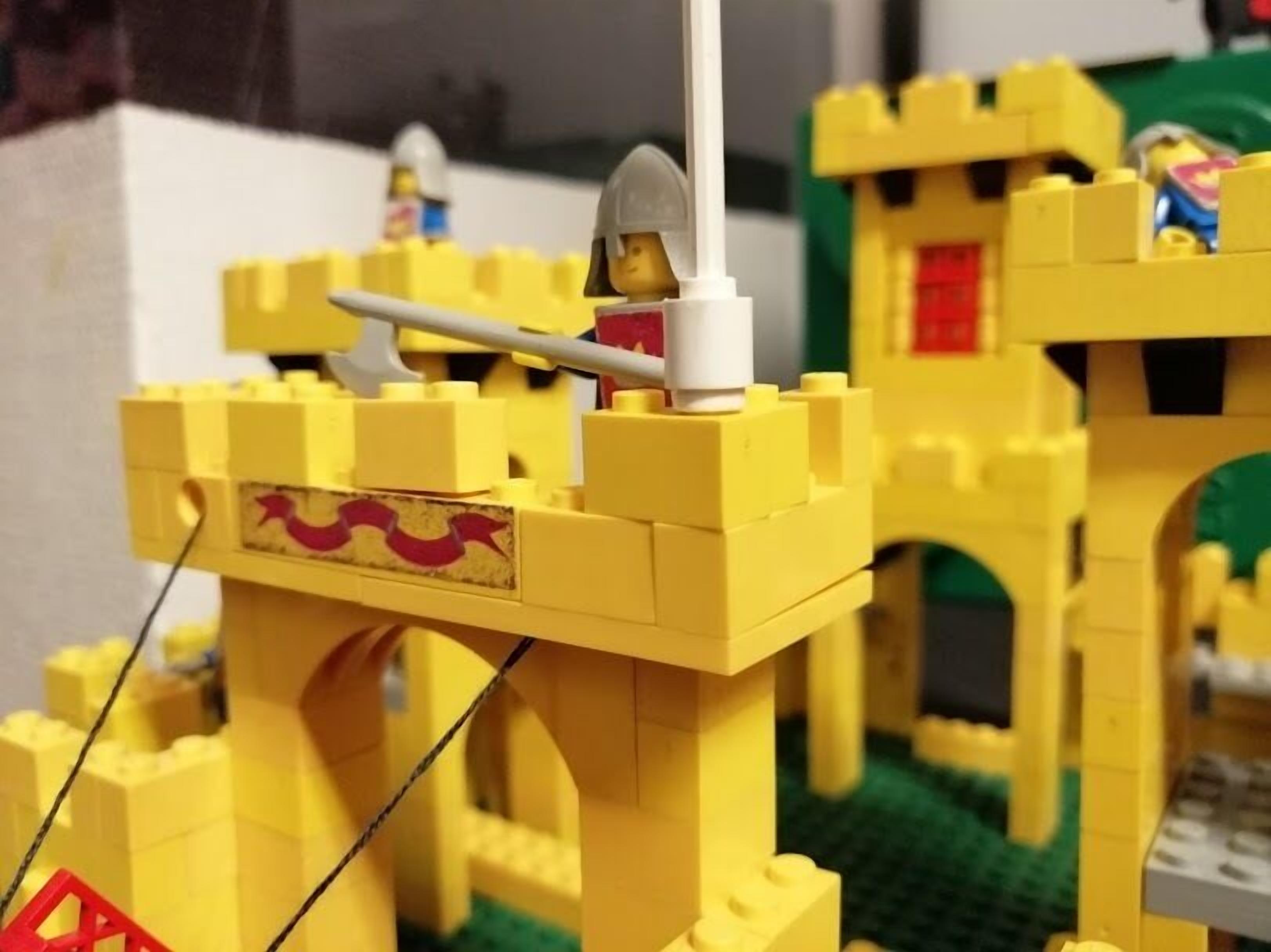Een LEGO-kasteel met een ophaalbrug en een figuur bovenop.