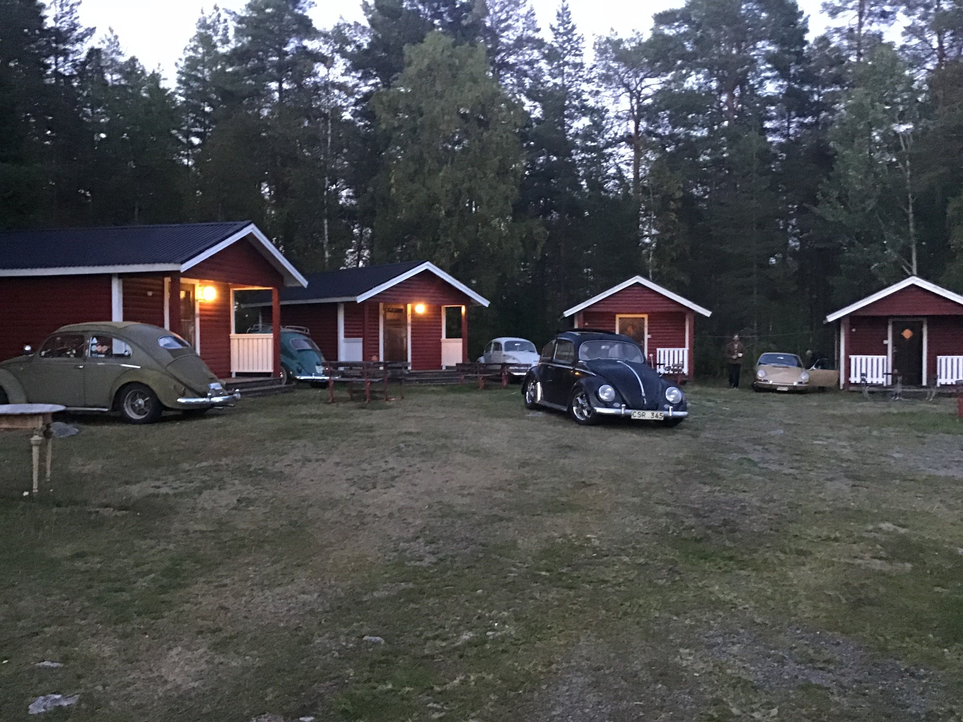 A row of cabins with a grassy yard and trees in the background.