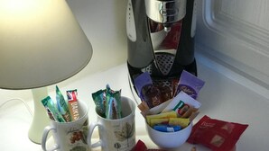 Ett bricka med två muggar, varav den ena innehåller kaffekapslar och den andra chokladkakor, samt en skål med olika sorters snacks.
