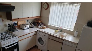 Ett kompakt kök med en gasspis, en tvättmaskin, en diskmaskin och ett handfat.