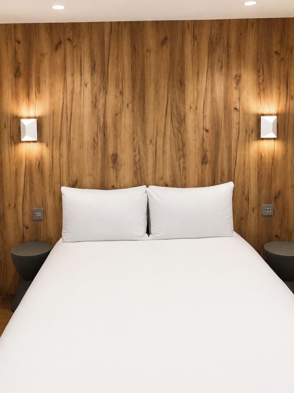 Ein Bett mit weißer Bettwäsche, zwei Nachttische und Holzvertäfelung an der Wand.
