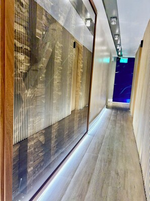 A modern hallway with wooden paneling, a glass partition, and a wooden floor. - RIOSHOUSE Henley (Henley-on-Thames)