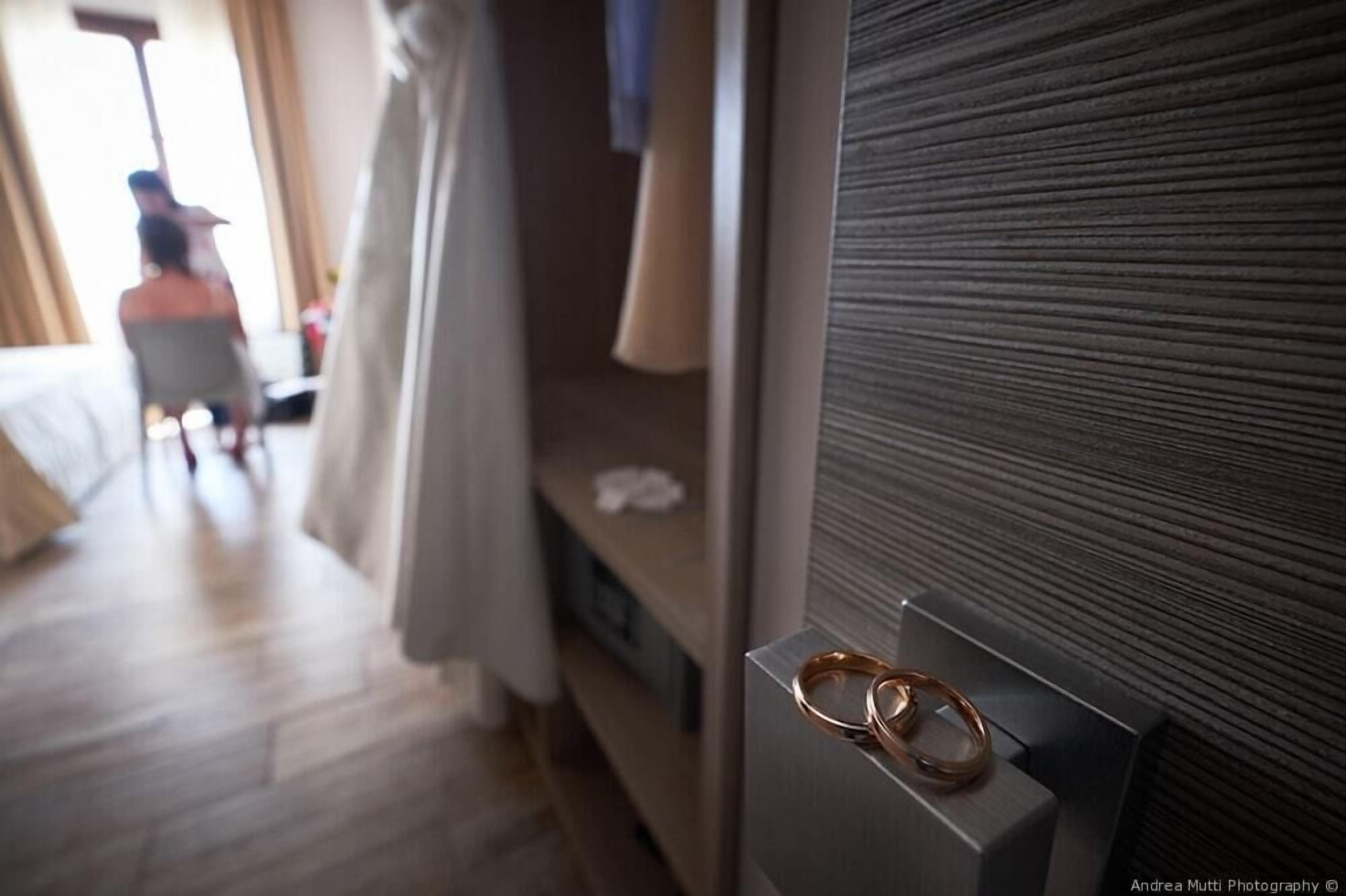 A hotel room with a bed, a window, and a wall-mounted display case with rings.