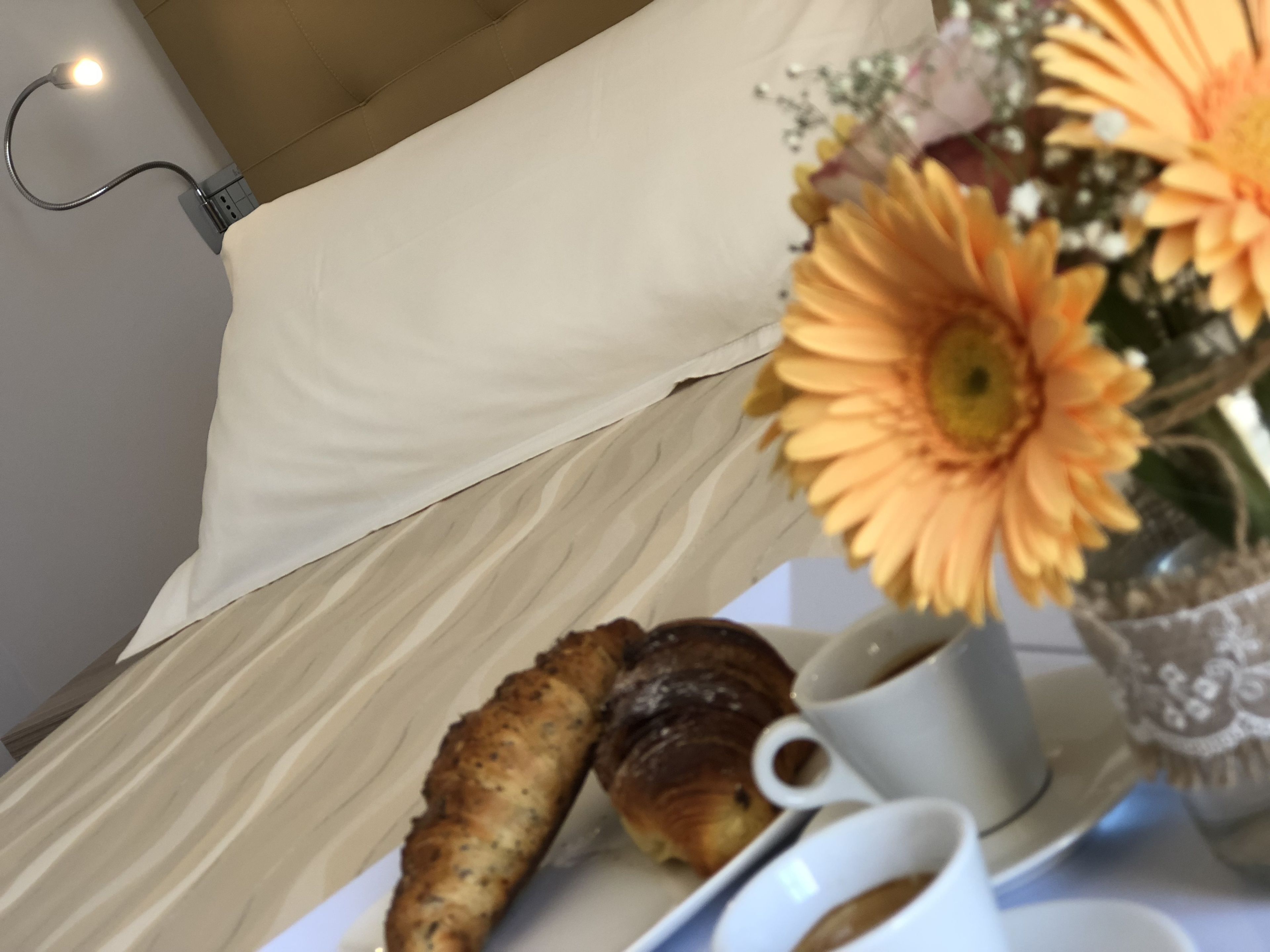 Une table avec une pâtisserie, une tasse de café et un vase rempli de fleurs.