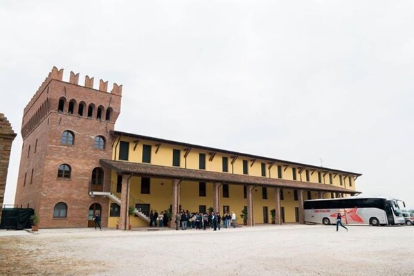 Un edificio grande con una torre destacada y un corredor cubierto.