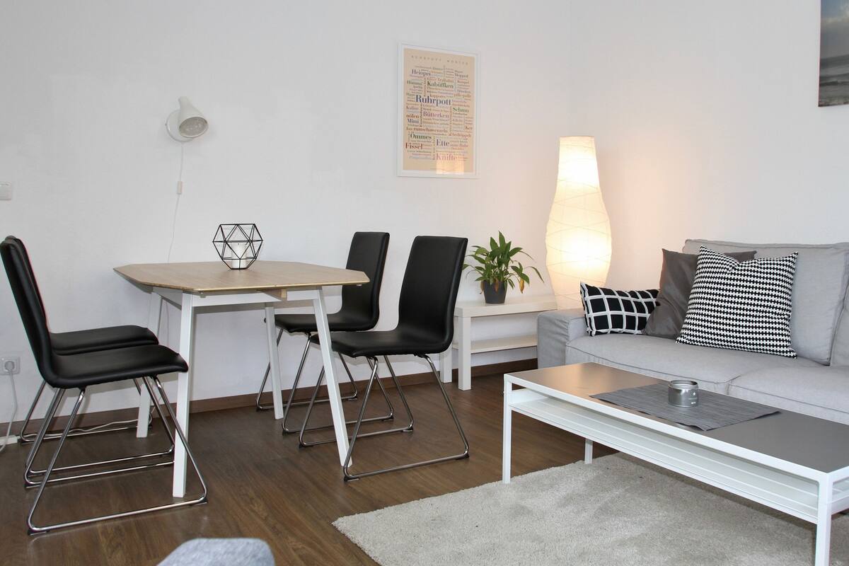 A modern living room with a dining table, chairs, a sofa, and a coffee table.