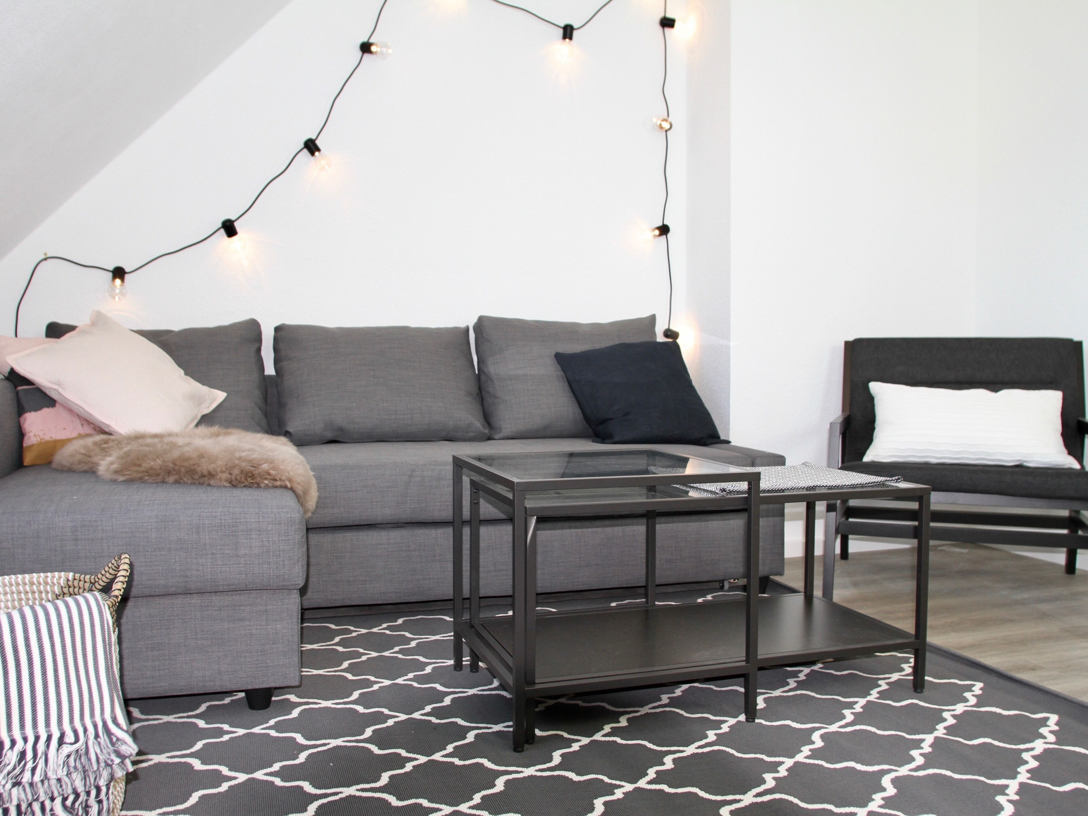 A modern living room with a grey sofa, a black coffee table, and a patterned rug.