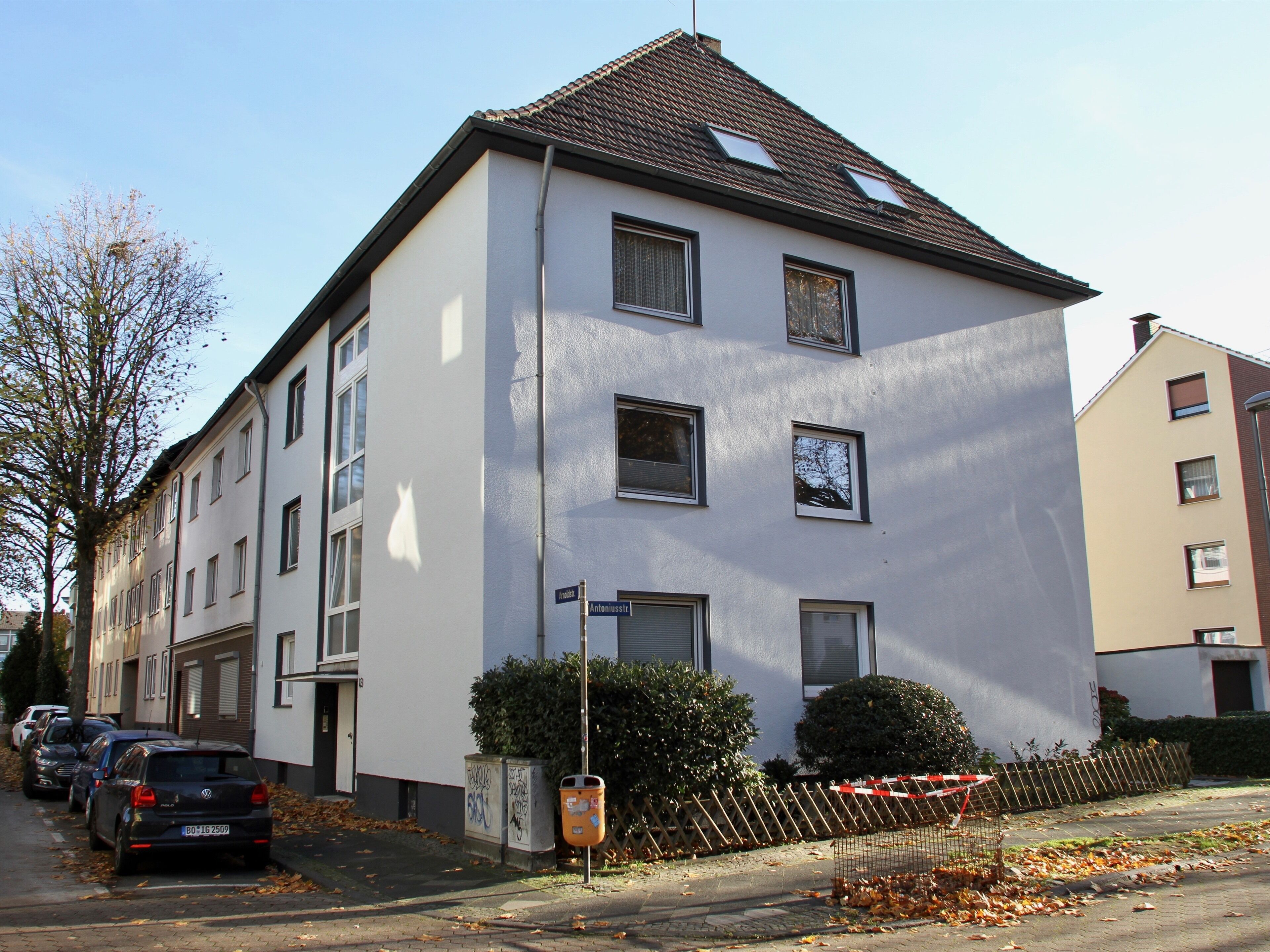 A multi-story residential building with a flat roof, several windows, and a visible street sign.