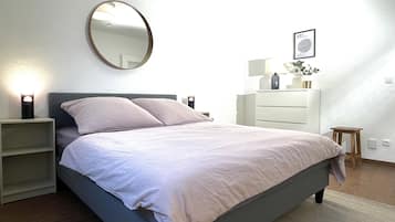 A bedroom with a bed, bedside tables, a dresser, a mirror, and a framed picture on the wall.