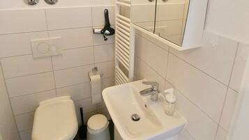 A small, compact bathroom with a toilet, bidet, and sink.