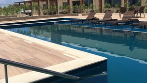 A swimming pool with lounge chairs and a building labeled "TROPICAL" in the background. - Tropical Mar Hotel (Aracaju)