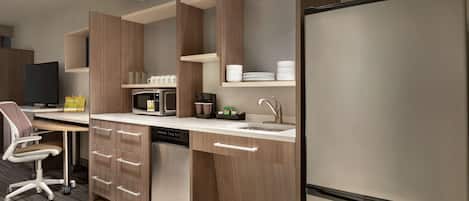 Una cocina moderna con armarios de madera, microondas integrado y un refrigerador grande.