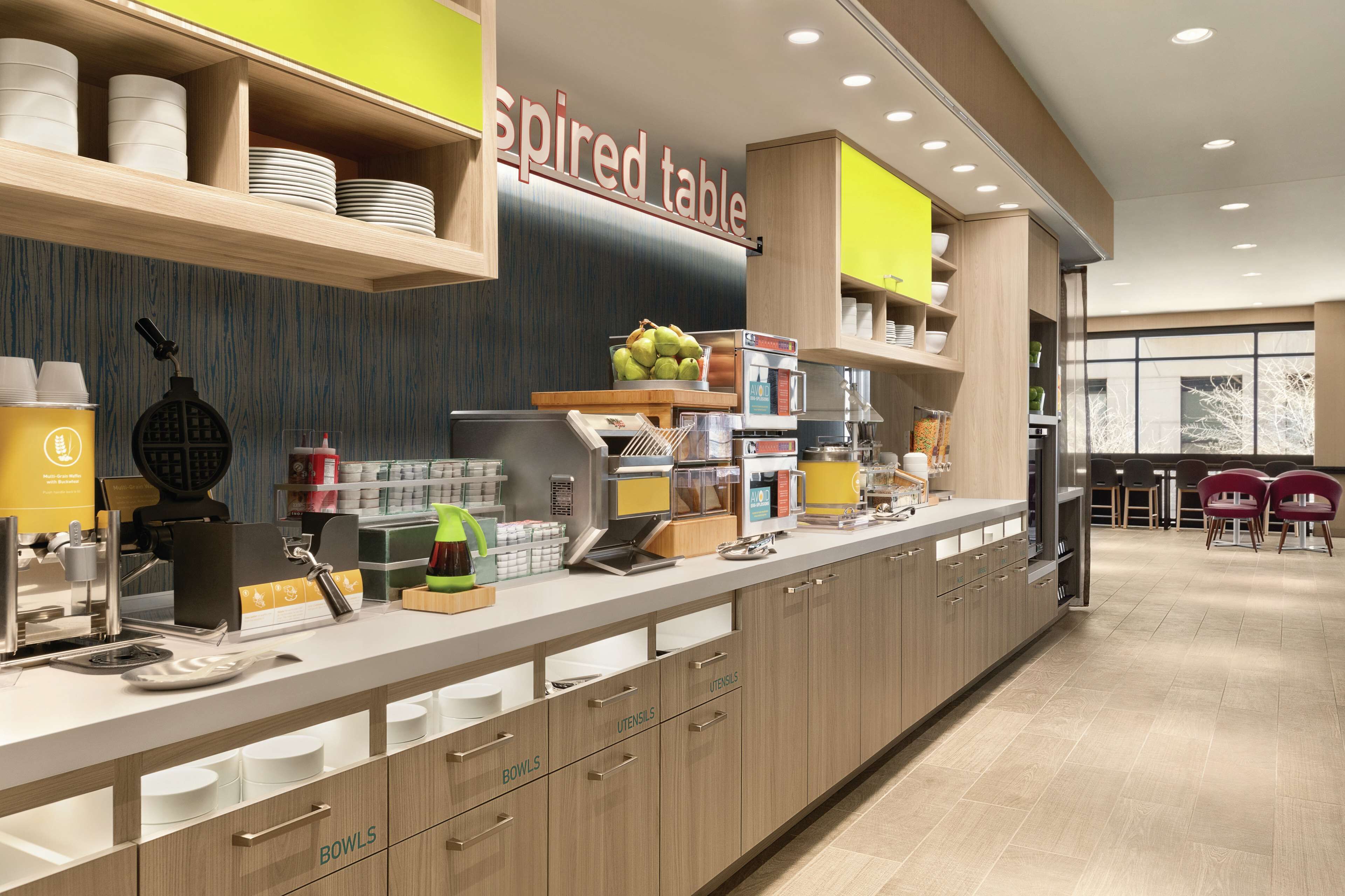 A modern kitchen with a long counter, labeled 'Inspired Table', featuring various kitchen appliances and utensils.