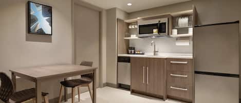 Una cocina moderna con zona de comedor, que incluye un microondas, refrigerador y armarios.