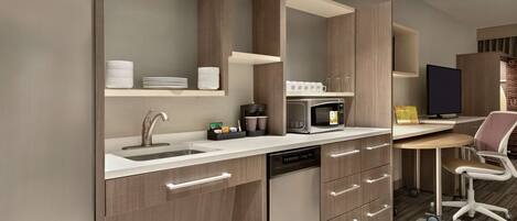 A modern kitchen with built-in appliances, a sink, and a dining area with a chair and table.