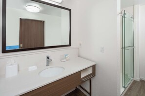 A modern bathroom with a large mirror, a sink, and a glass shower enclosure. - Hampton Inn & Suites San Diego Airport Liberty Station (San Diego)