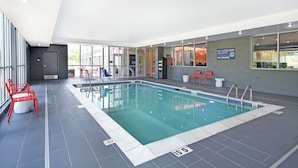 An indoor swimming pool with clear markings, red chairs, and a sign indicating no lifeguard on duty. - Tru by Hilton Grand Rapids Airport (Grand Rapids)