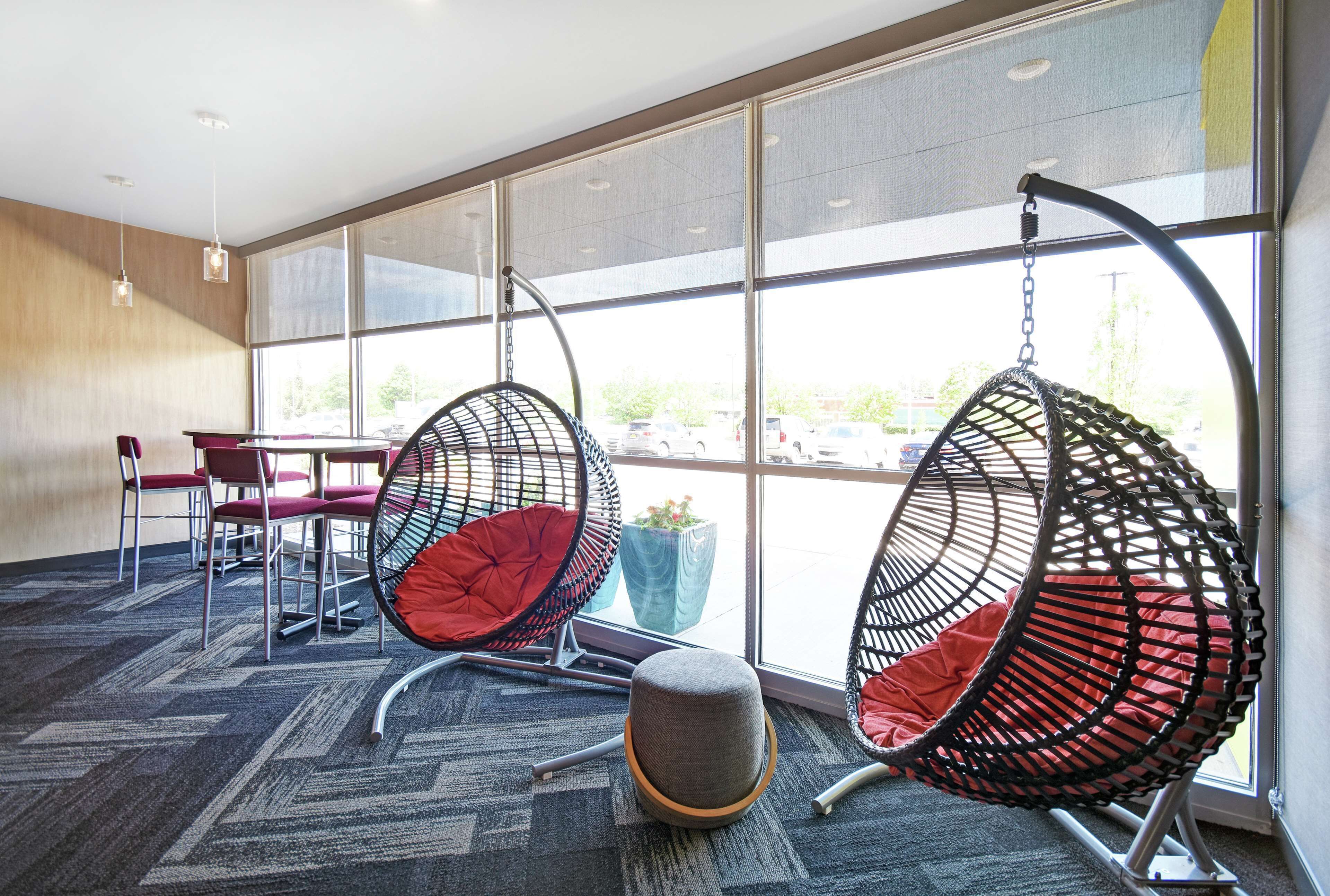 A modern interior with large windows, hanging chairs, and a carpeted floor.