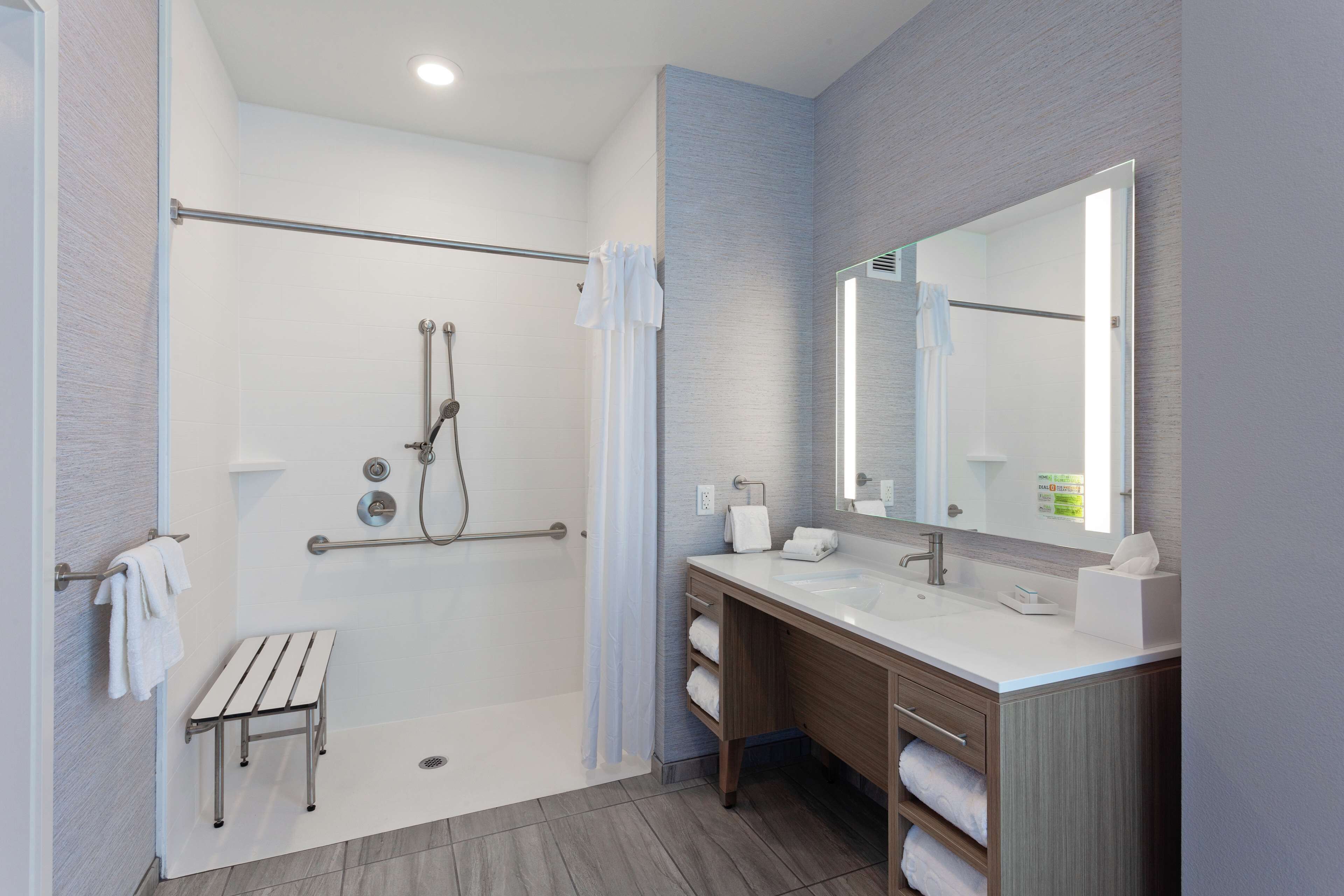 A modern bathroom with a walk-in shower, a large mirror, and a vanity with a sink.