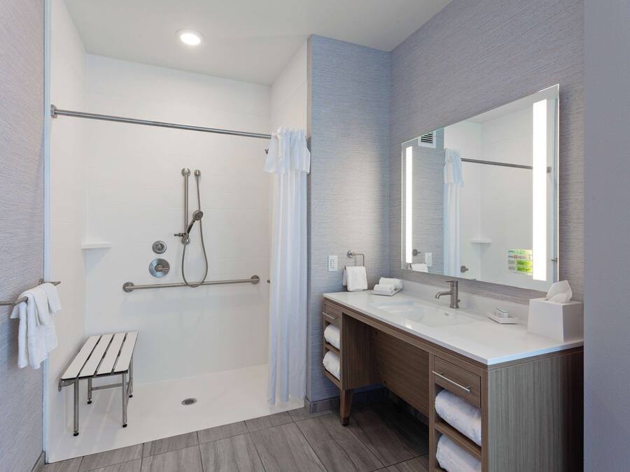 A modern bathroom with a walk-in shower, a large mirror, and a vanity with a sink.