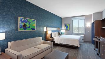 A hotel room with a bed, a sofa, a desk, and a nightstand.