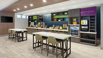 A modern kitchen with a long counter, bar stools, and a refrigerator.