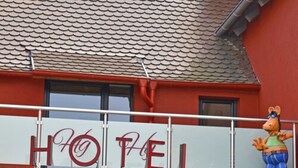 A hotel sign with the name "HOTEL GÜNZBURG City" and a mascot figure on the balcony.